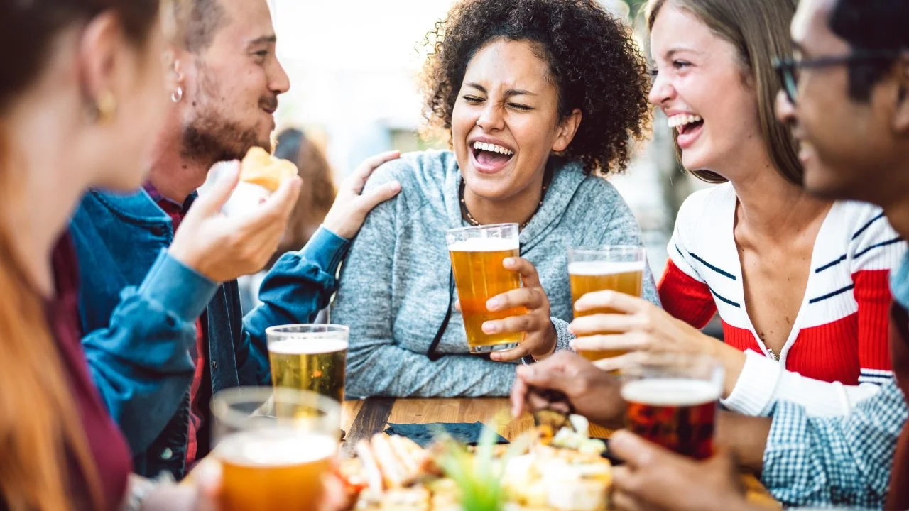 Group of friends enjoying beers and laughter at a casual dining table
