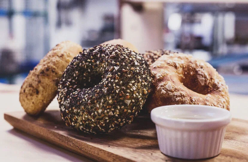 Artisan bagels with assorted toppings on a wooden board