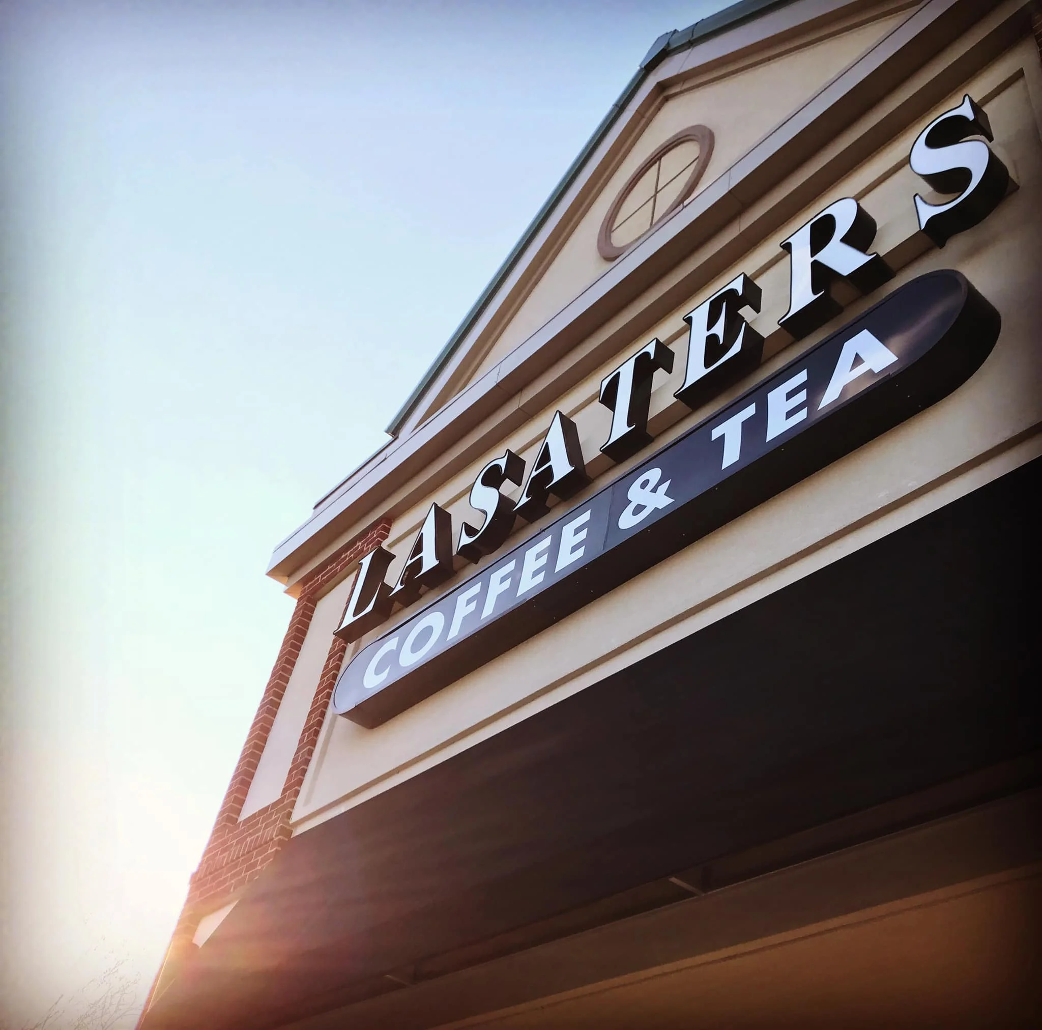 Coffee shop logo sign with sun peeking from behind building.