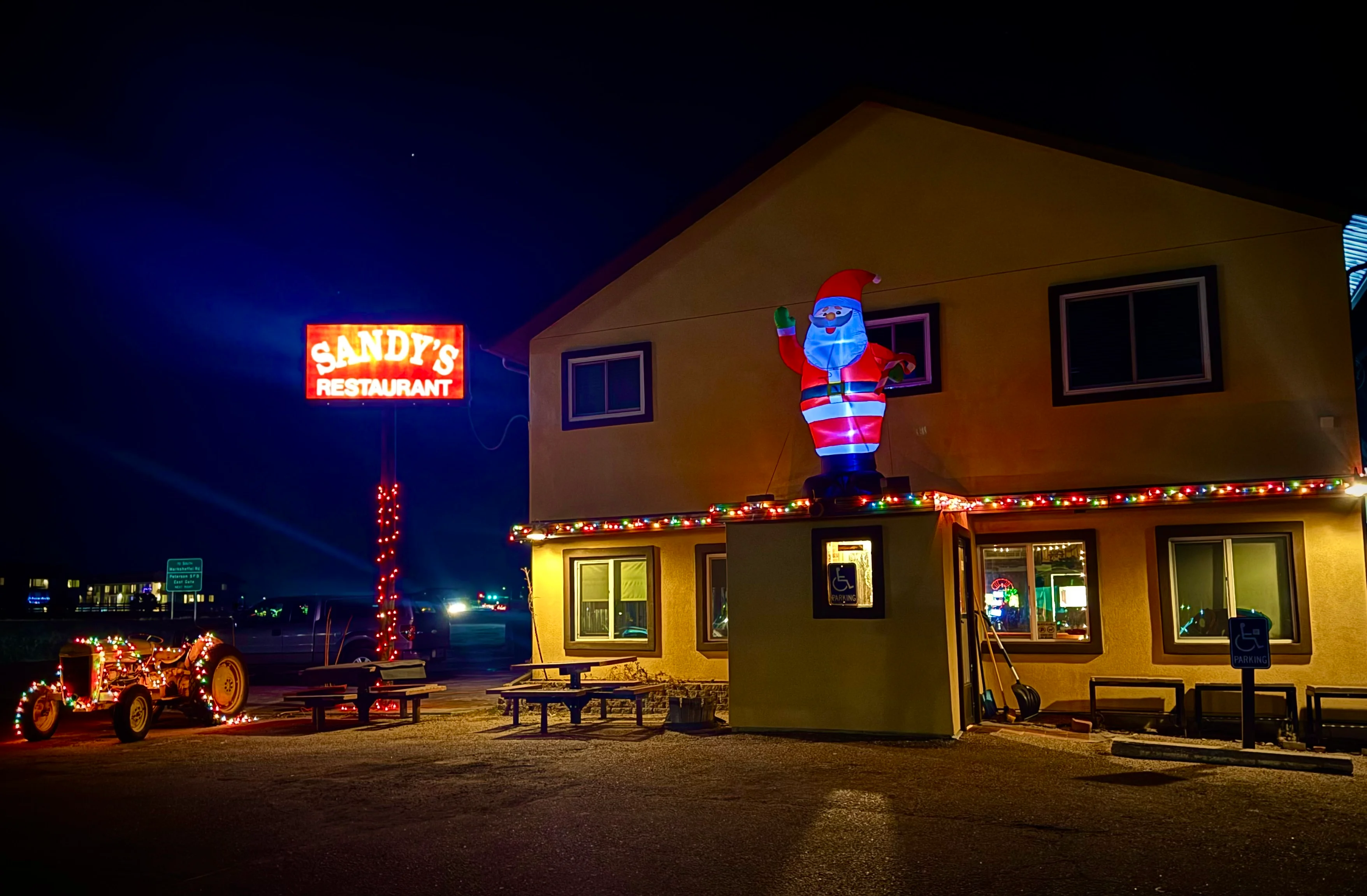 A logo depicting a yellow building with a tall tree and a sign, representing a family restaurant in Colorado Springs, CO.