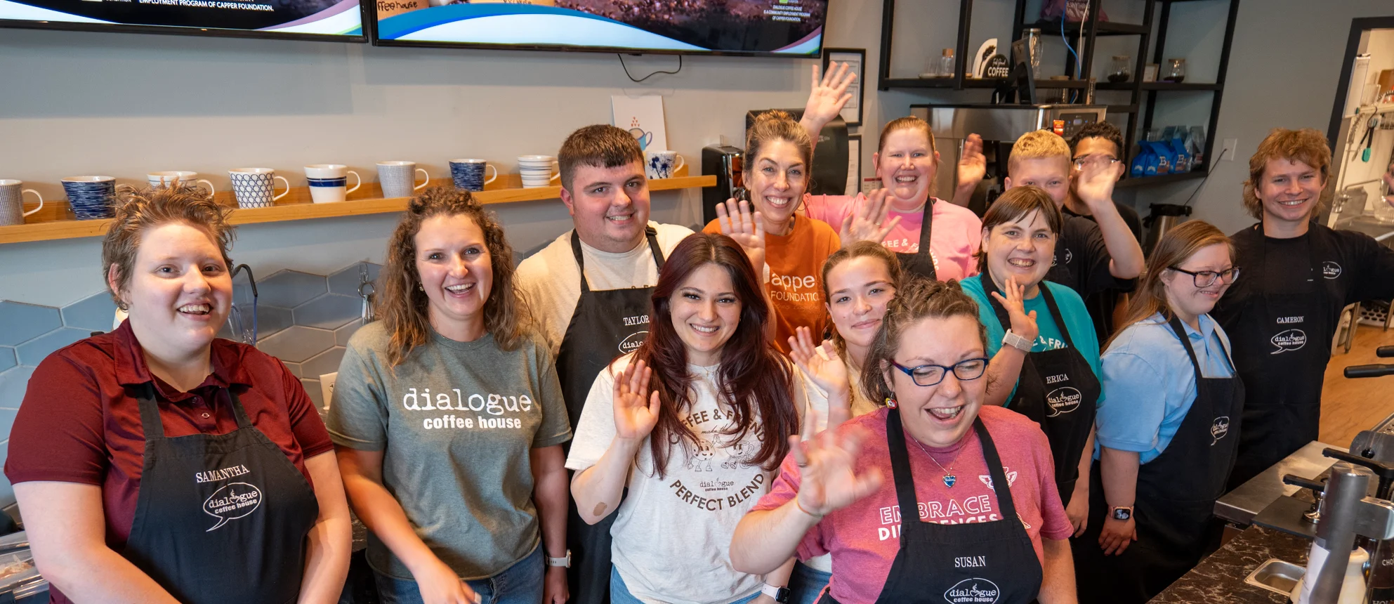 Smiling coffee shop staff comprised of a diverse group of individuals several with intellectual and developmental disabilities