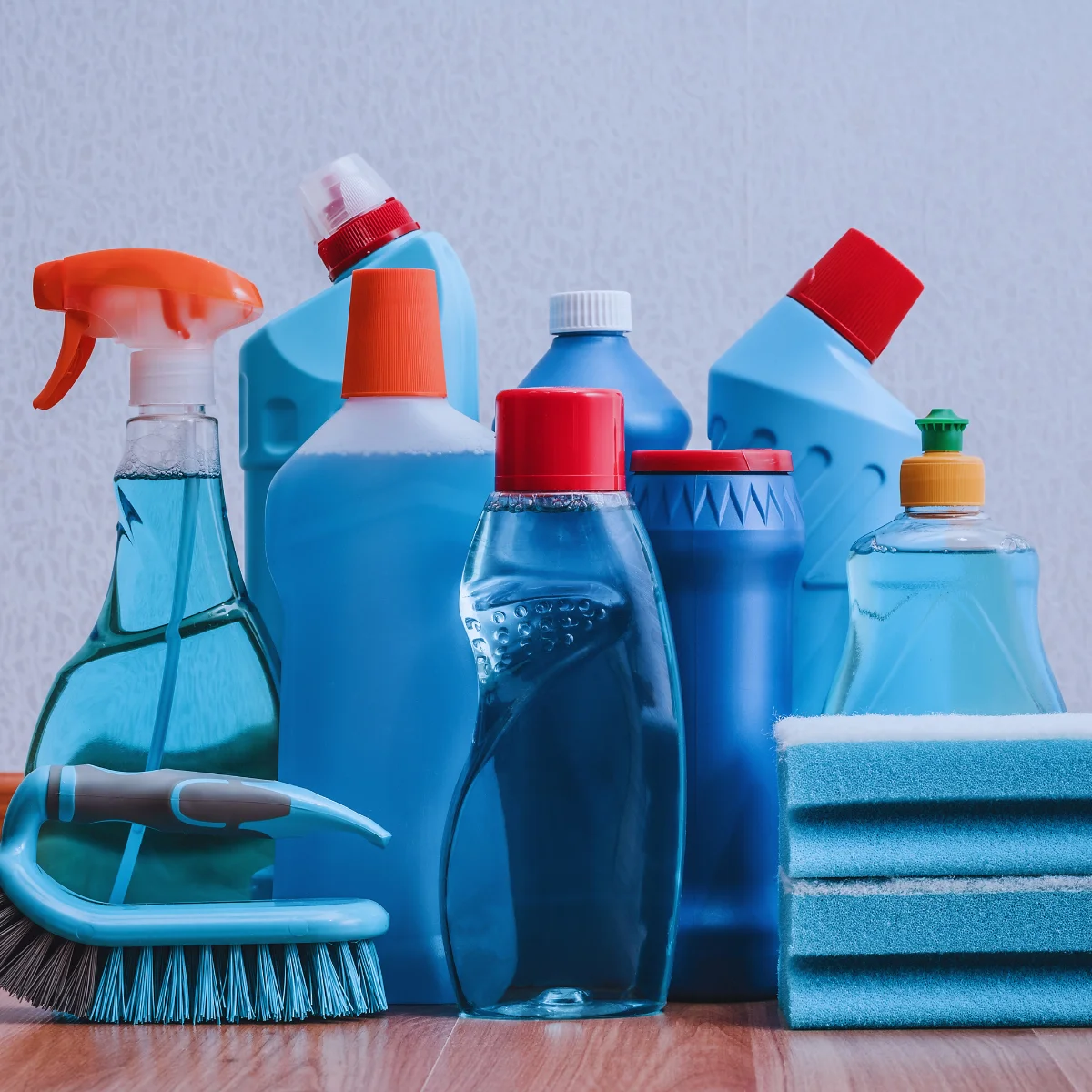 Assorted cleaning supplies in blue bottles and sponges