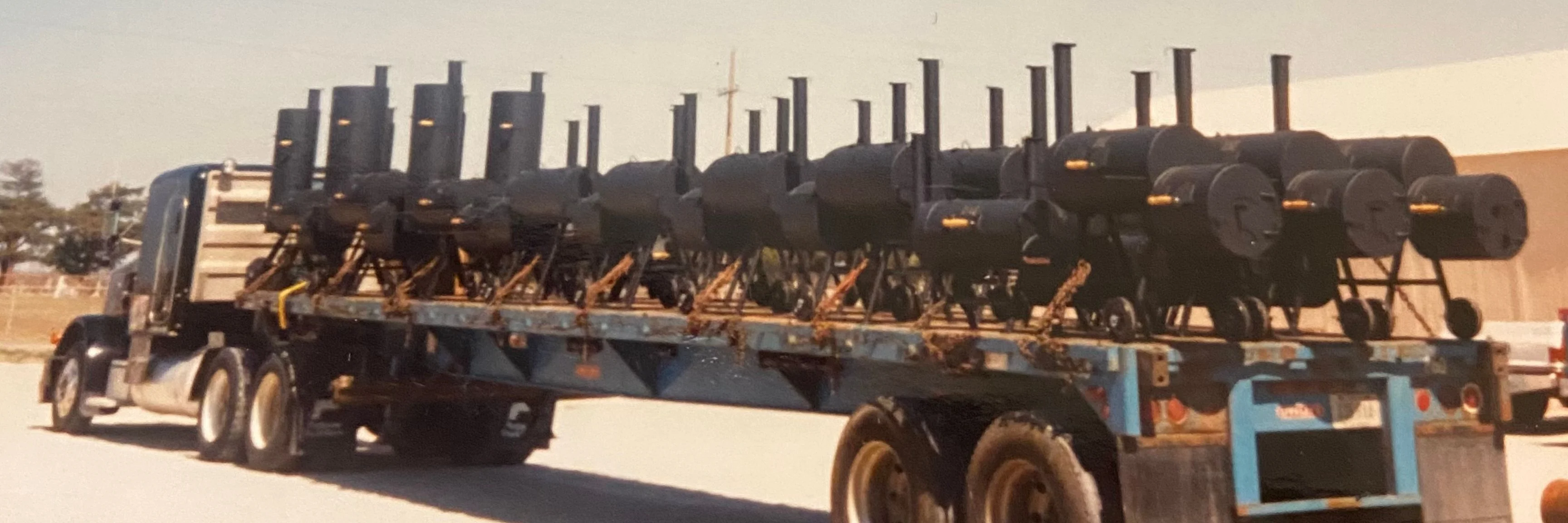 Truck transporting multiple barbecue smokers on a flatbed trailer