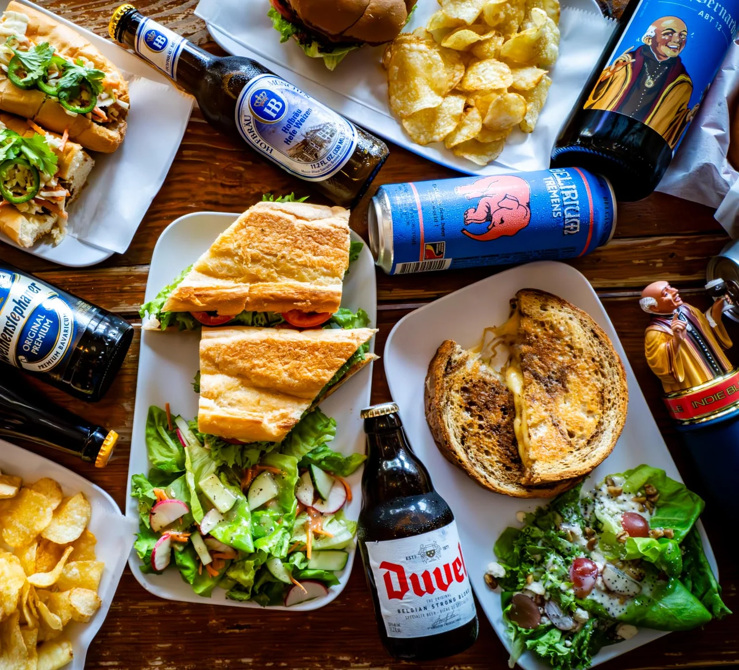 Assorted sandwiches and beers on a rustic wooden table
