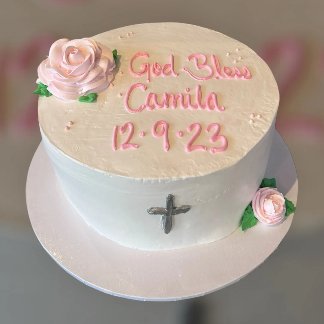 Elegant cake decorated for a special occasion with pink roses and a cross