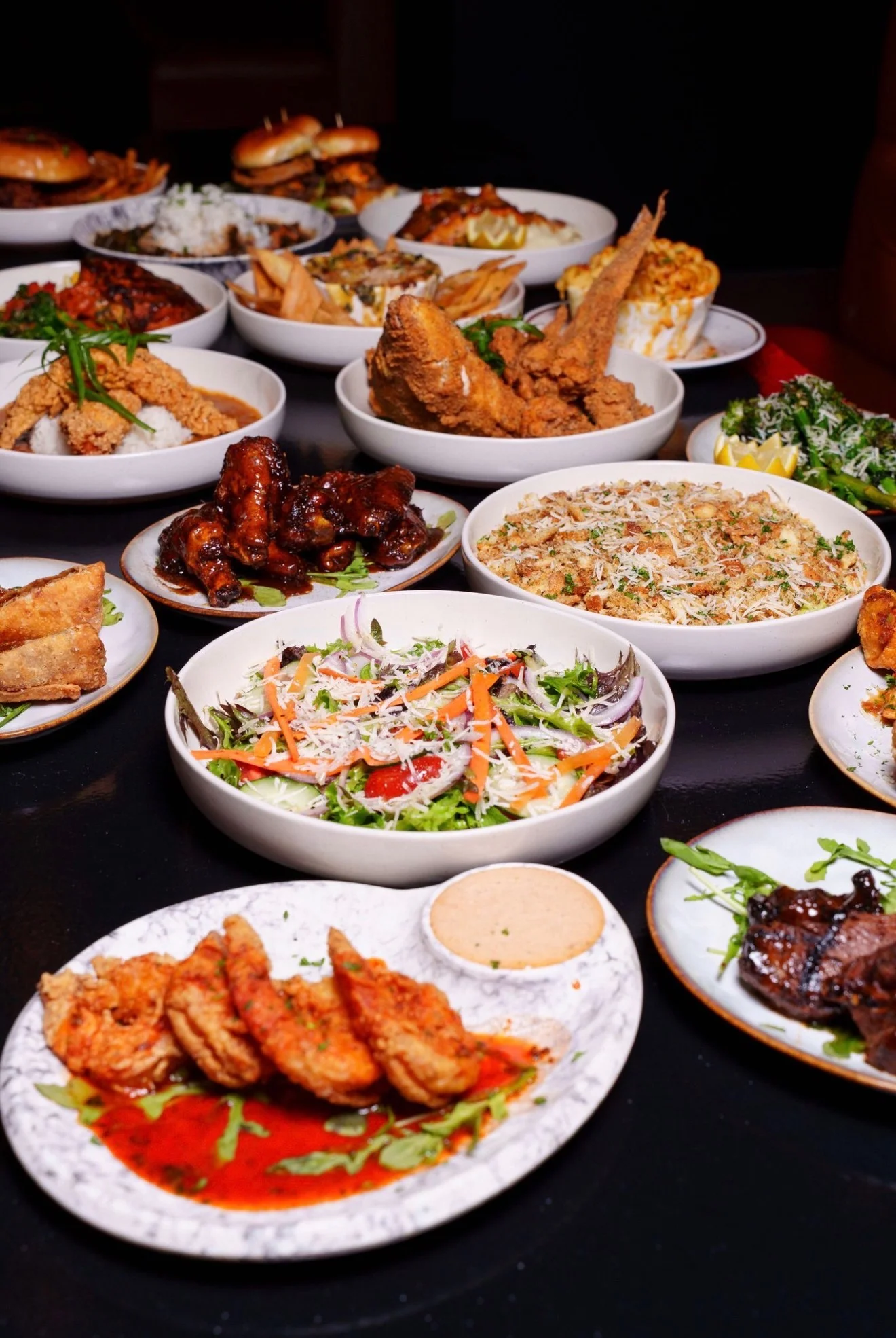 A table filled with a variety of delicious dishes including fried chicken, salads, and sides, presented in bowls.