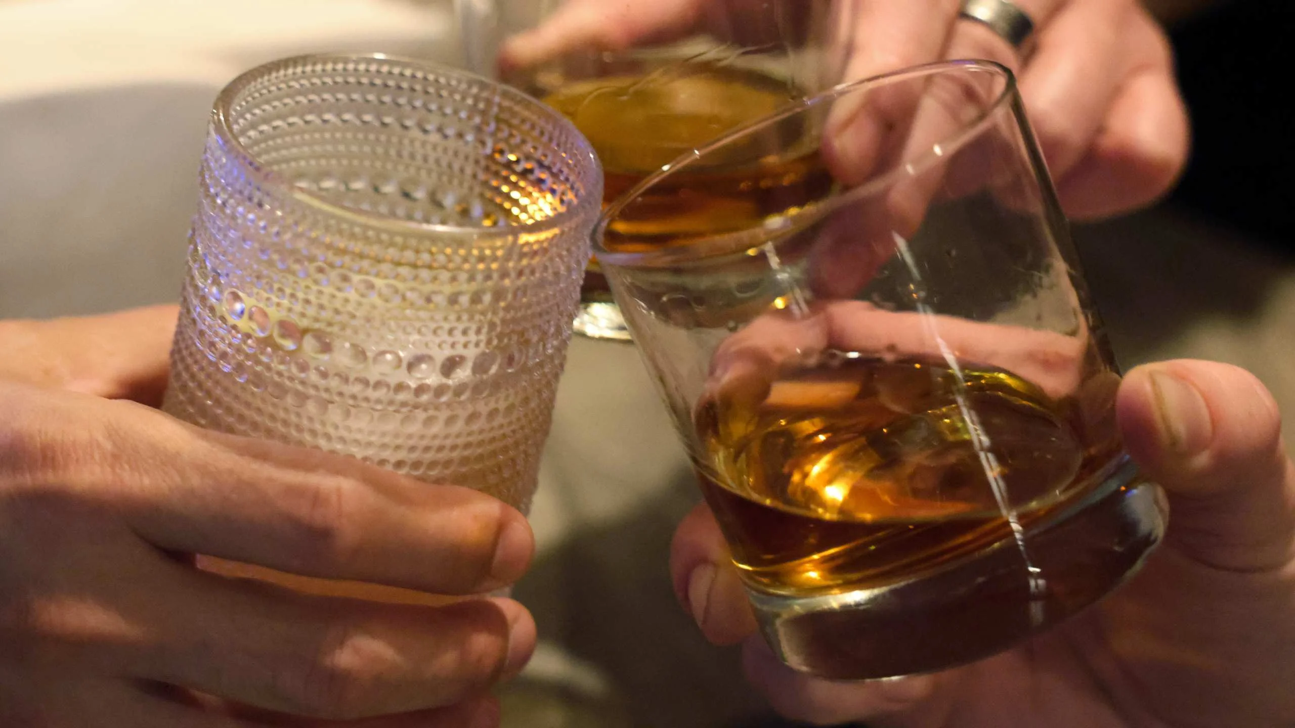 Cheers with whiskey glasses in a social gathering