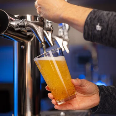Bartender pouring a cold beer into a glass