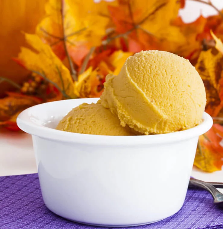 Pumpkin ice cream in a white bowl with autumn leaves