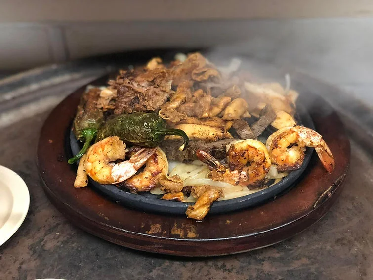 Sizzling fajitas with shrimp and beef on a hot skillet