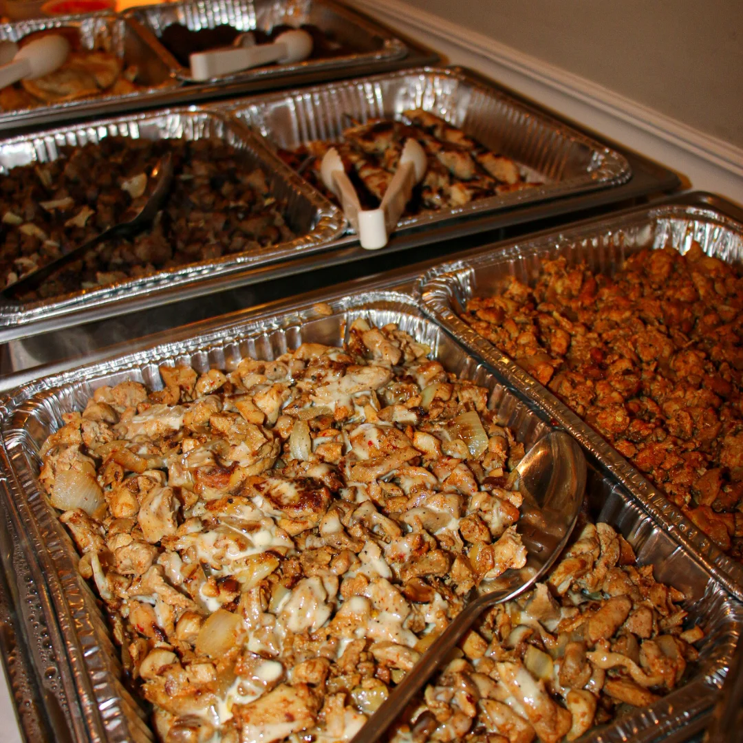 Various trays of grilled chicken and sides at a restaurant buffet.