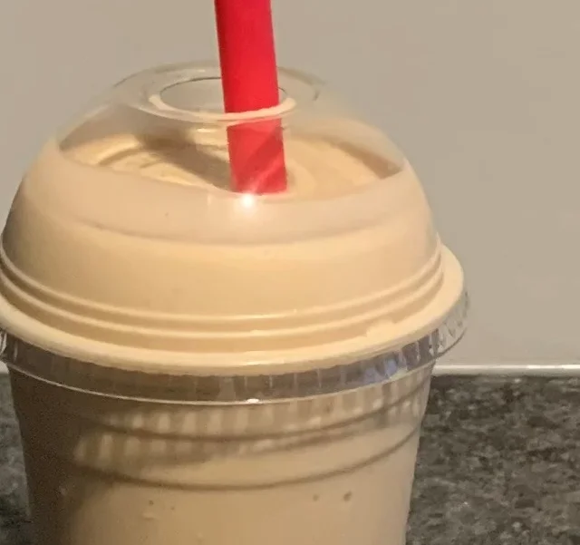 Creamy milkshake in a clear cup with a red straw