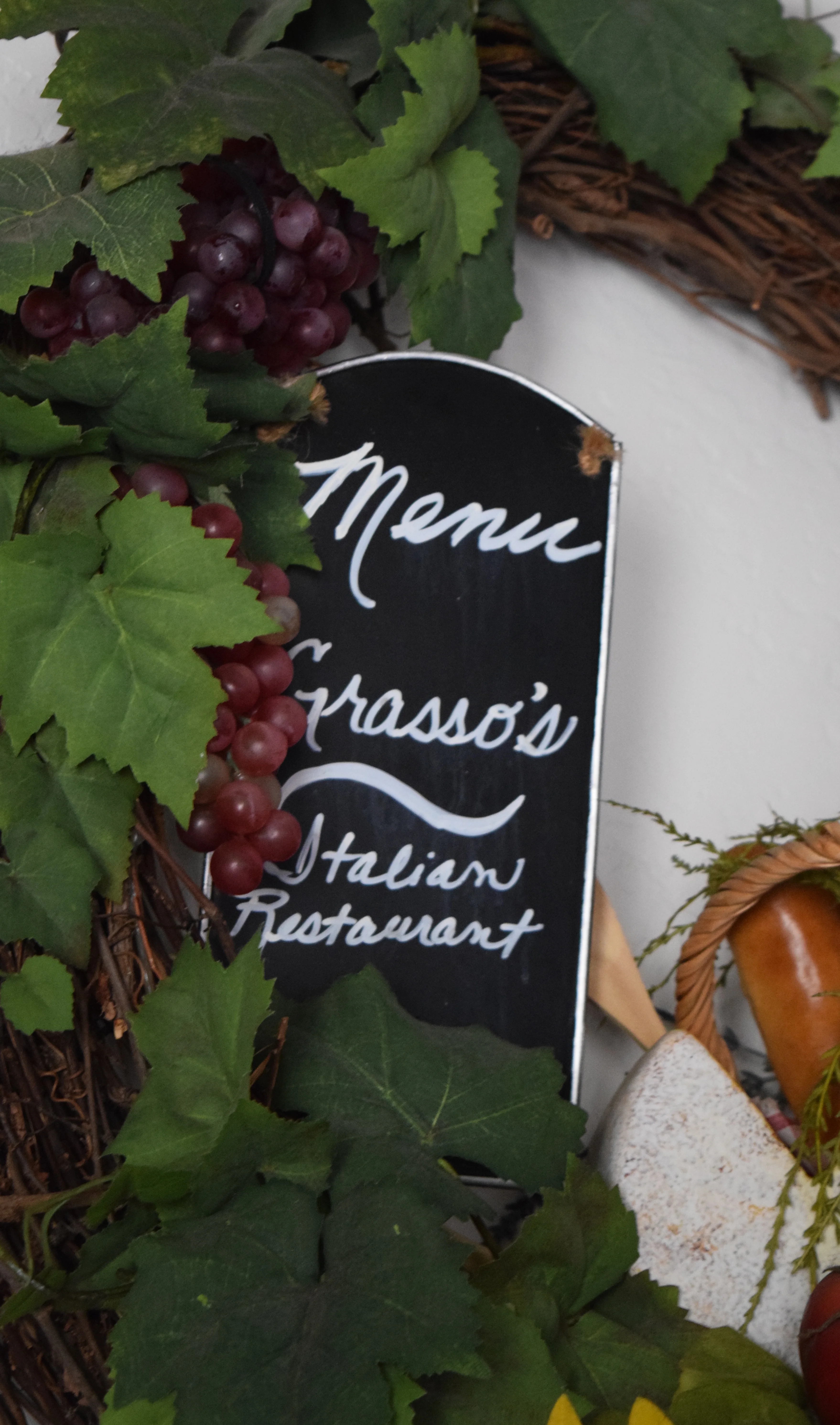 Chalkboard menu sign for Grasso's Italian Restaurant with grapevine decor