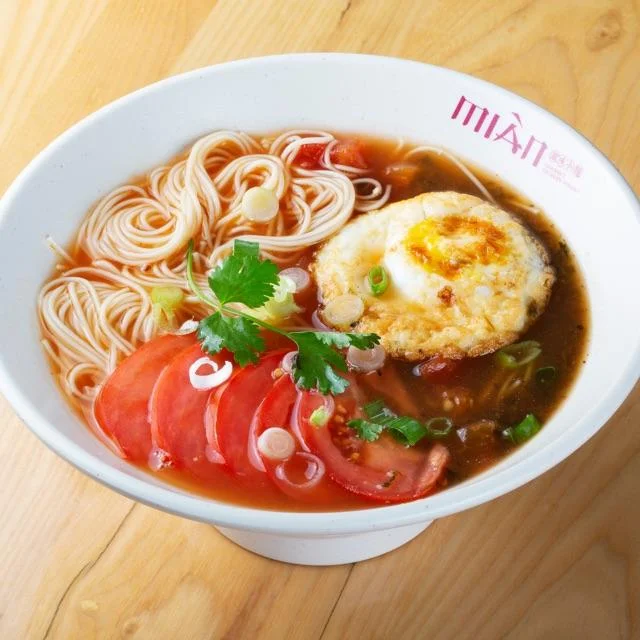 Plate of Huaxing fried egg noodles with colorful vegetables and egg.