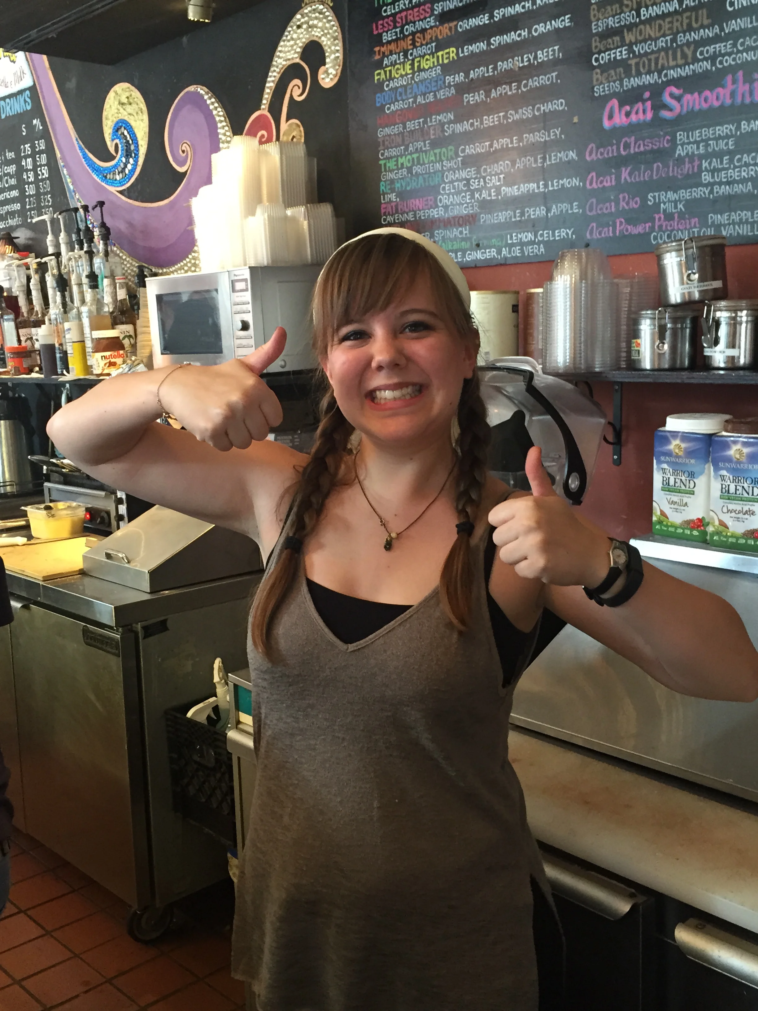 Smiling staff member giving thumbs up in a vibrant café setting