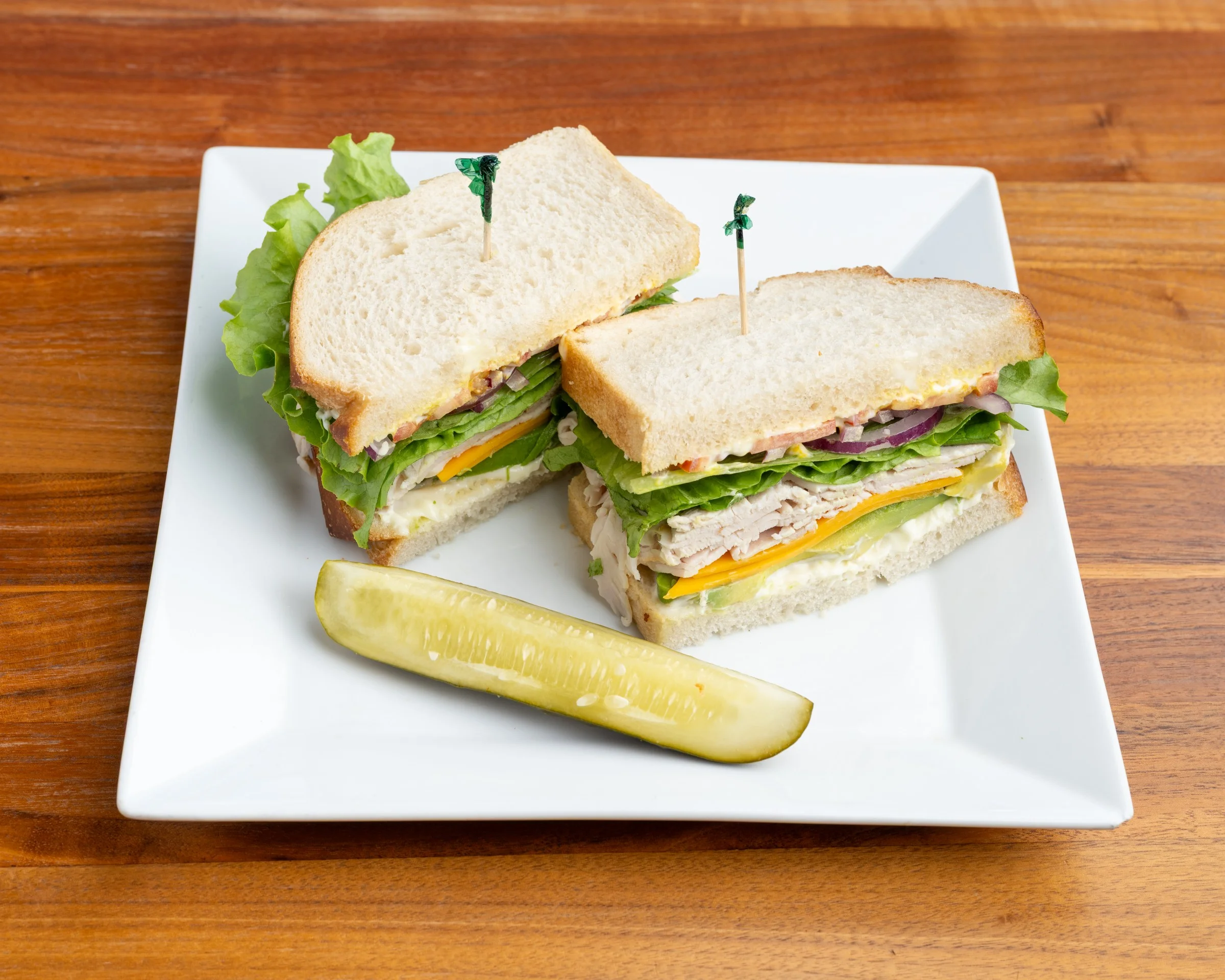 Turkey and cheese sandwich with lettuce and a pickle