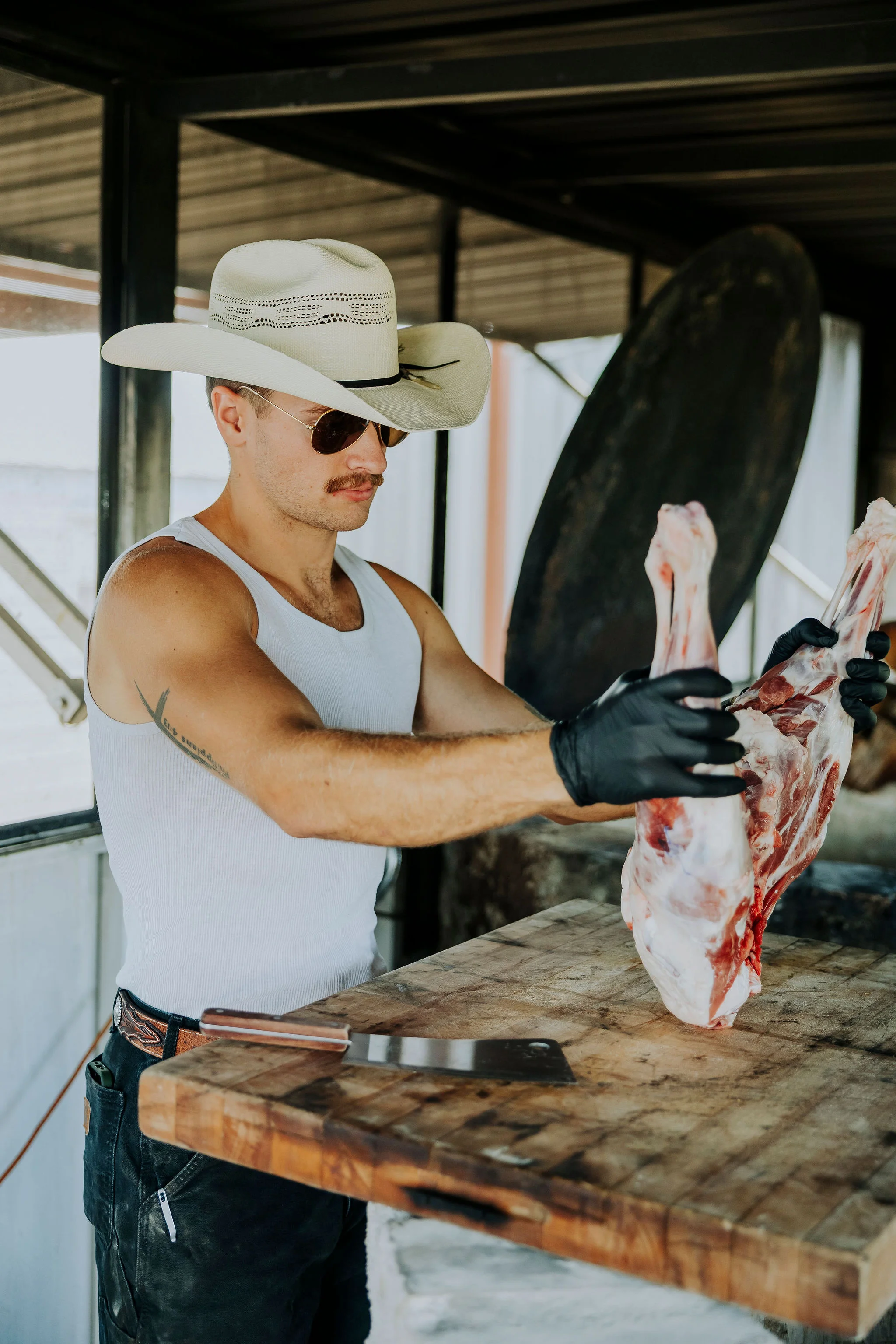 Butcher preparing meat with a cleaver in a rustic setting