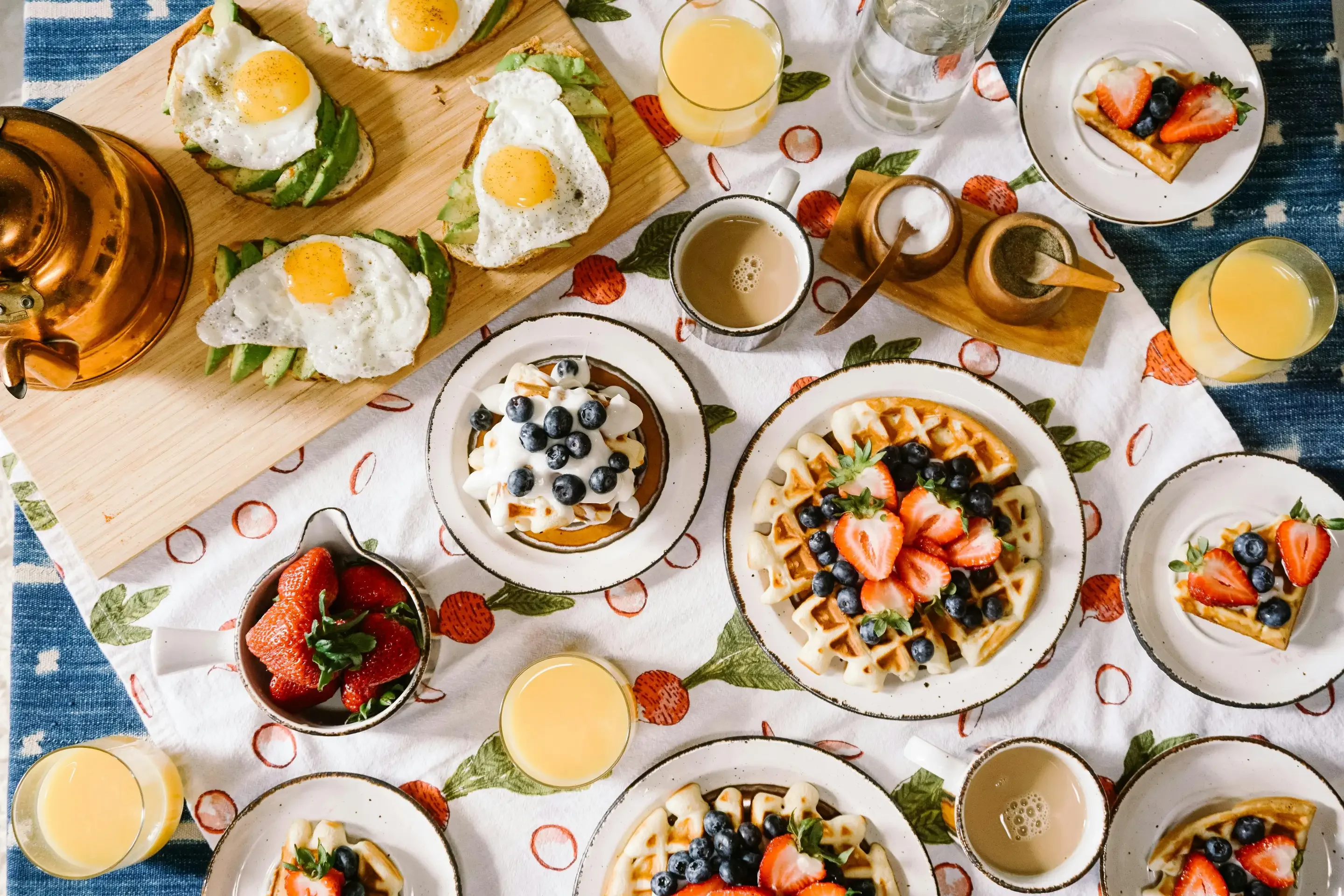 Brunch spread featuring waffles, avocado toast, and fresh fruit