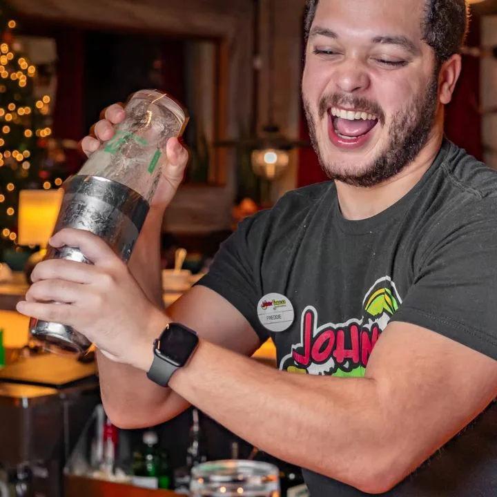 Bartender shaking a cocktail at a lively bar