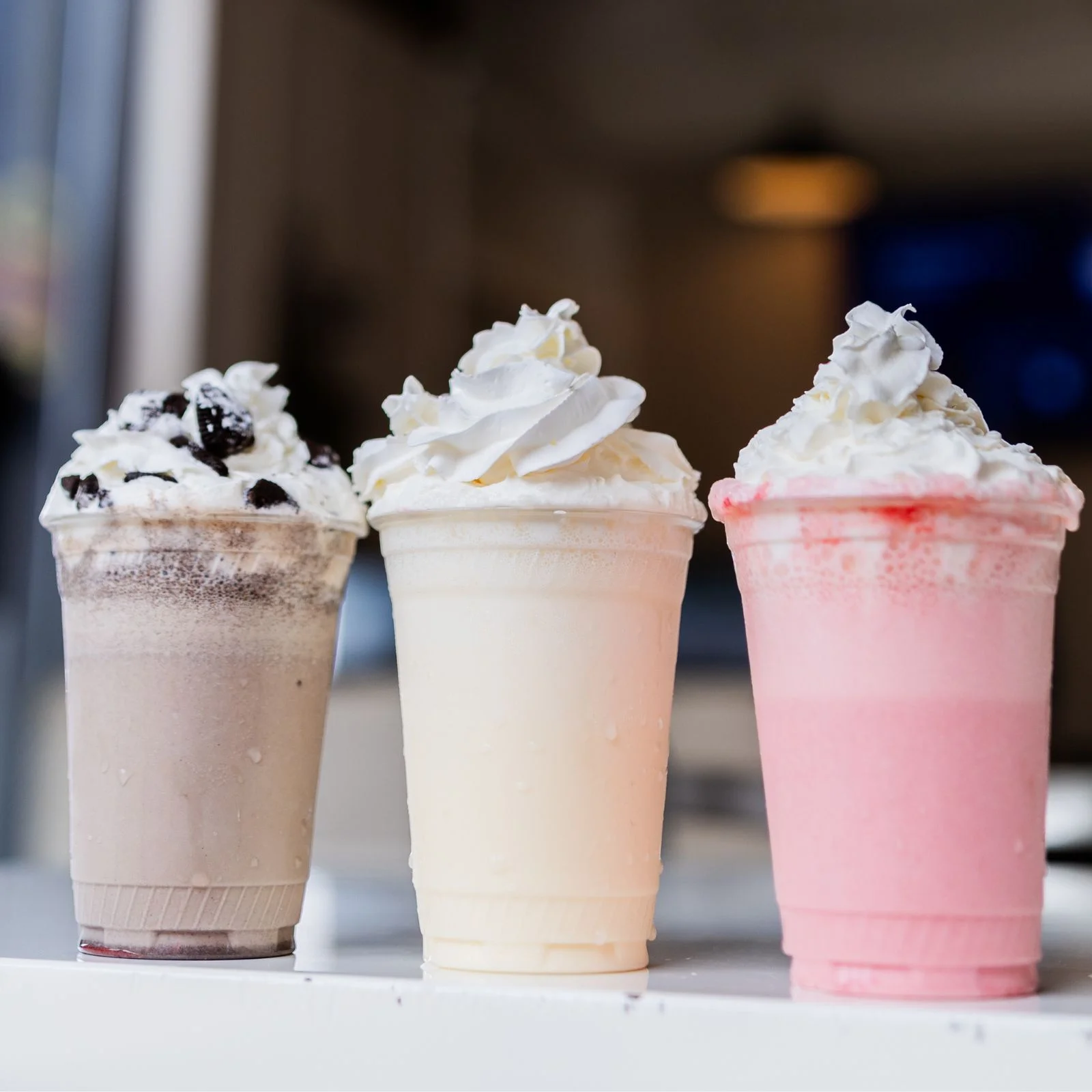 Three colorful milkshakes topped with whipped cream