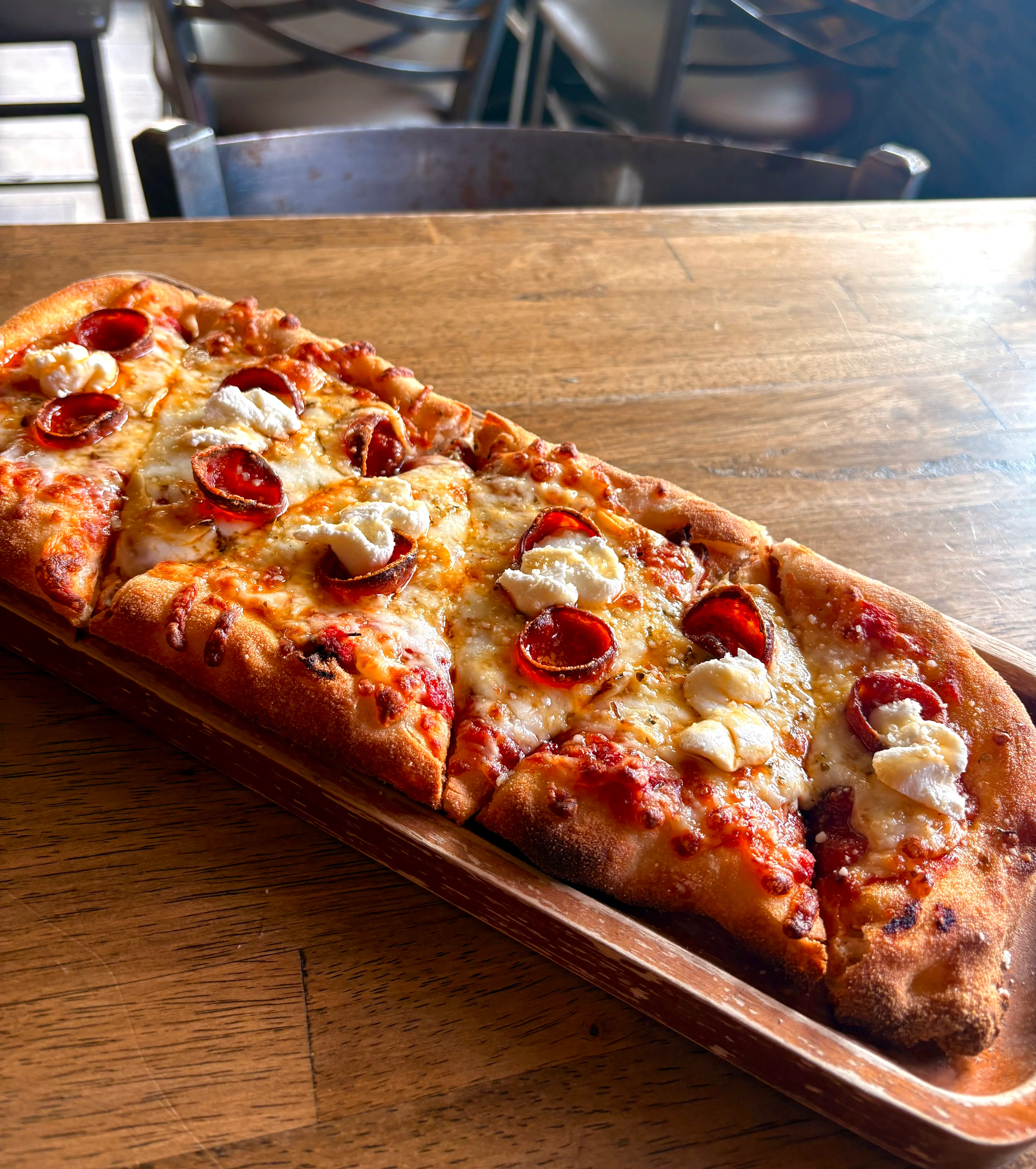 Pepperoni flatbread pizza served in a rustic restaurant