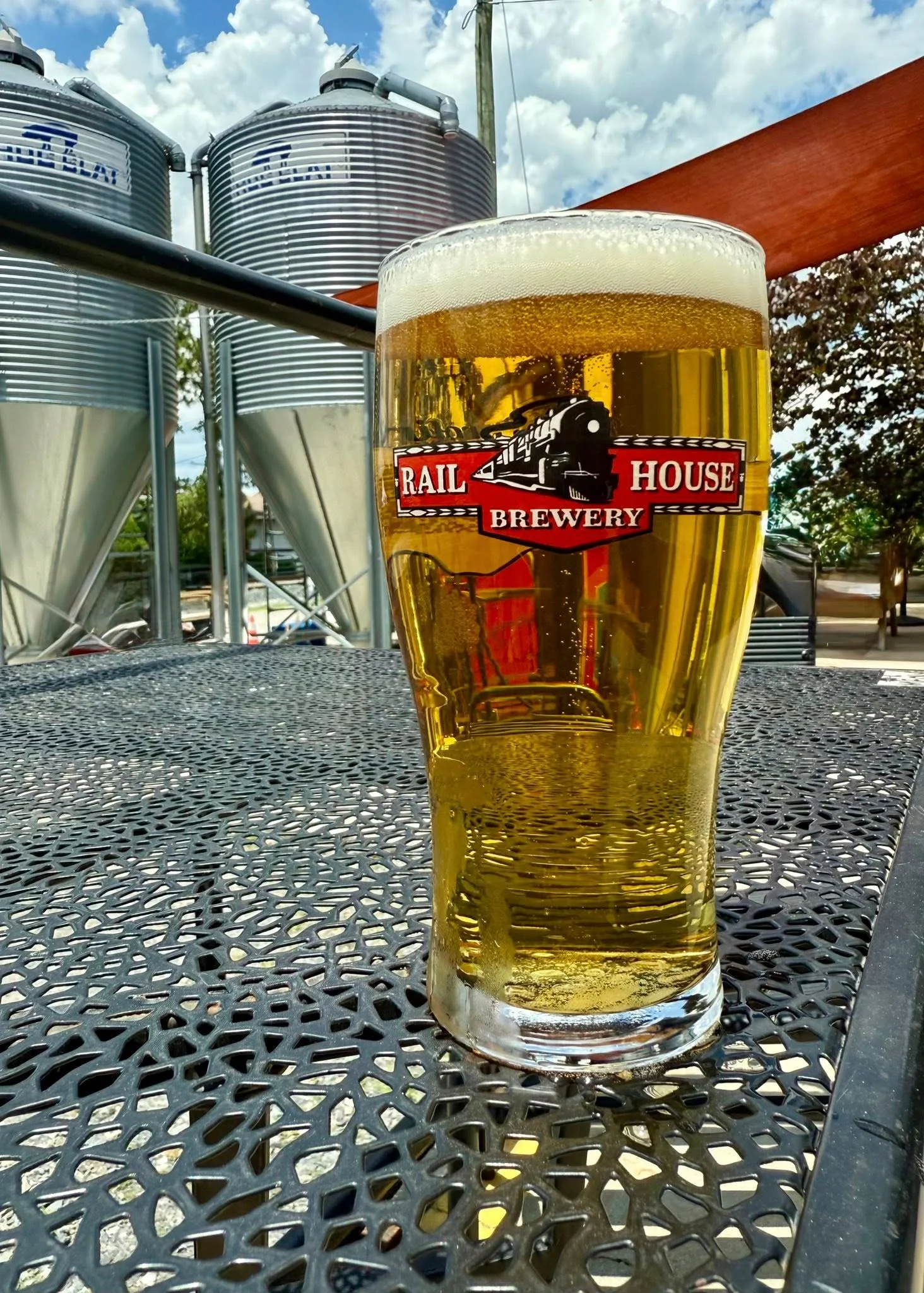 Glass of craft beer at a brewery with fermentation tanks