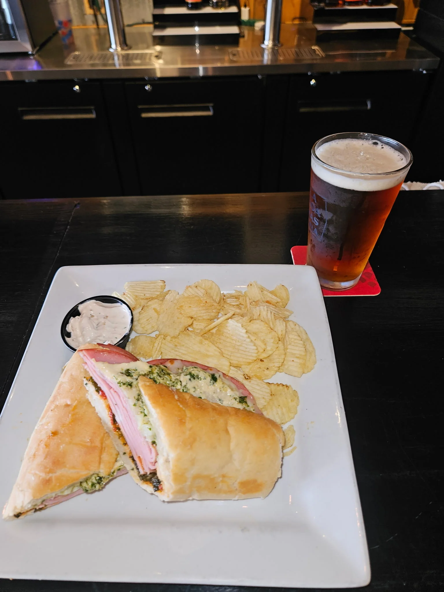 A glass of beer being filled, with a basket of snacks in the background.