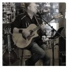 Musician performing live with acoustic guitar in a cozy venue