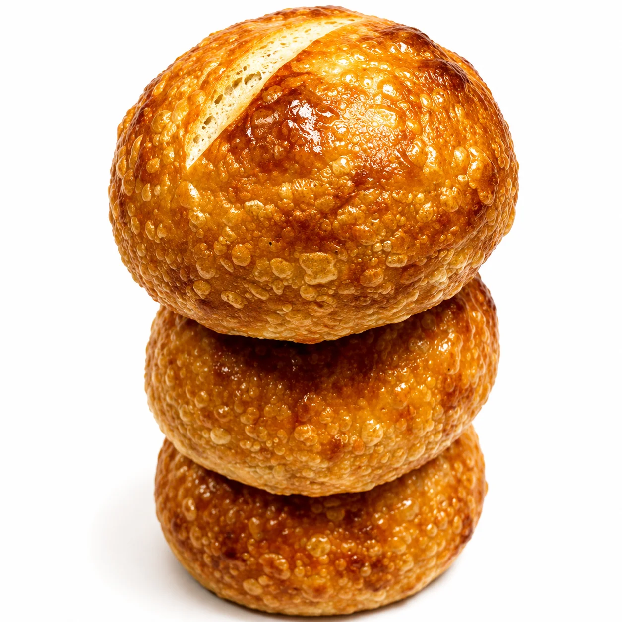 Three golden, flaky bread rolls stacked on top of each other.