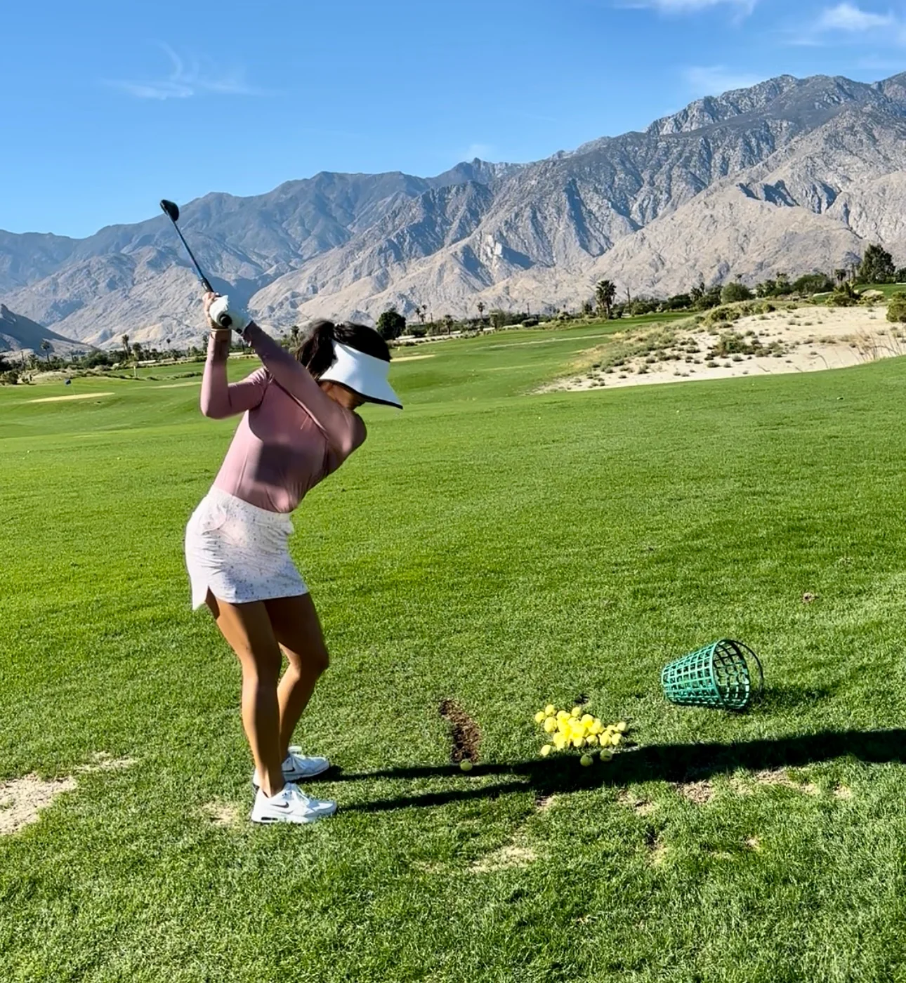 Golfer practicing swing on a sunny day with mountains in the background