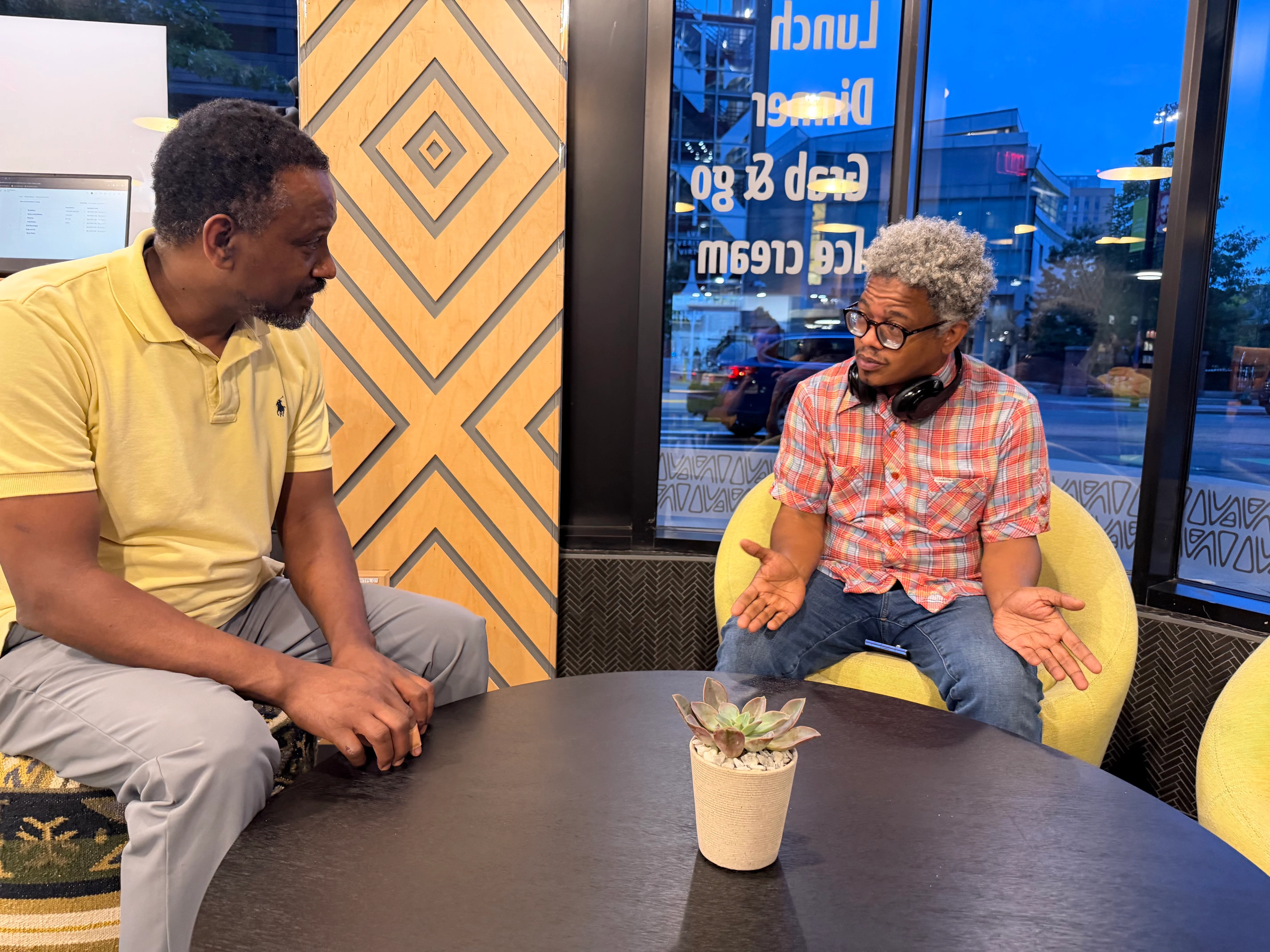 Two men engaged in conversation in a vibrant grocery store