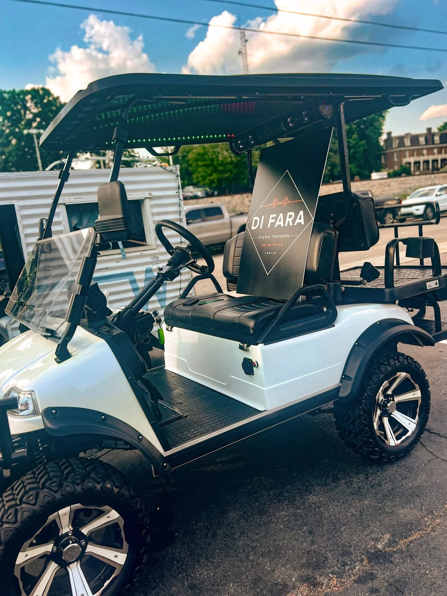 Golf cart with a sign for Di Fara Pizza Tavern, outdoor setting.