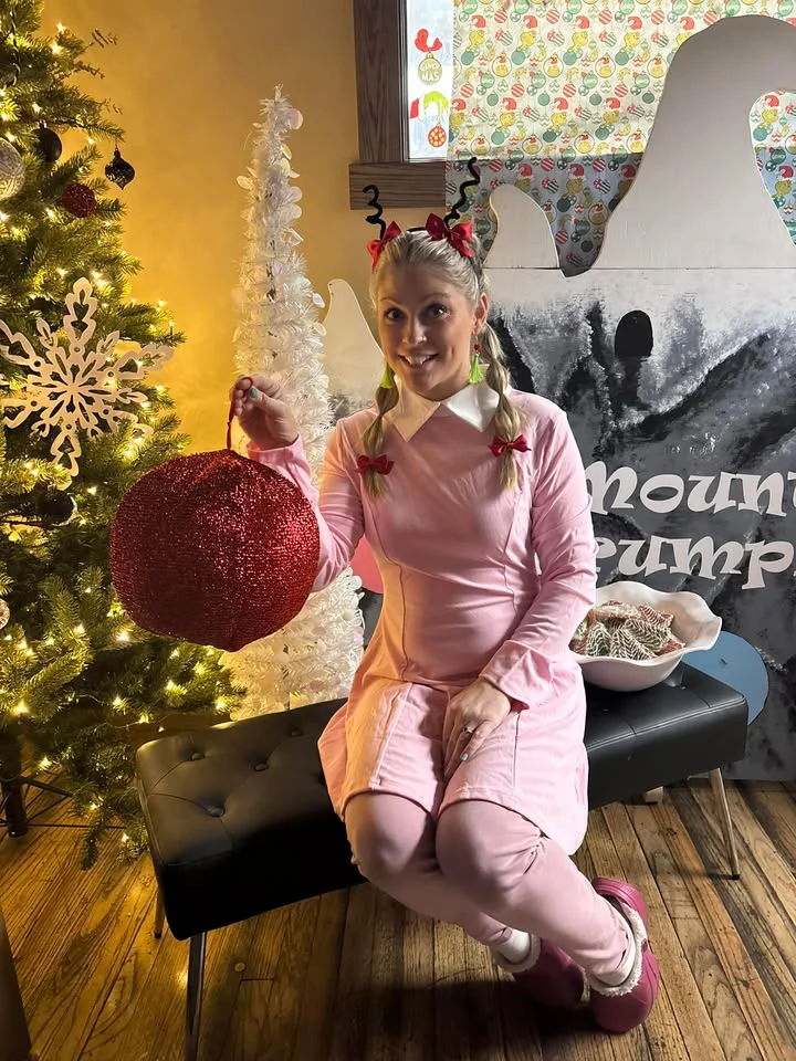 Festive holiday decor with a woman in pink holding a glittery ornament