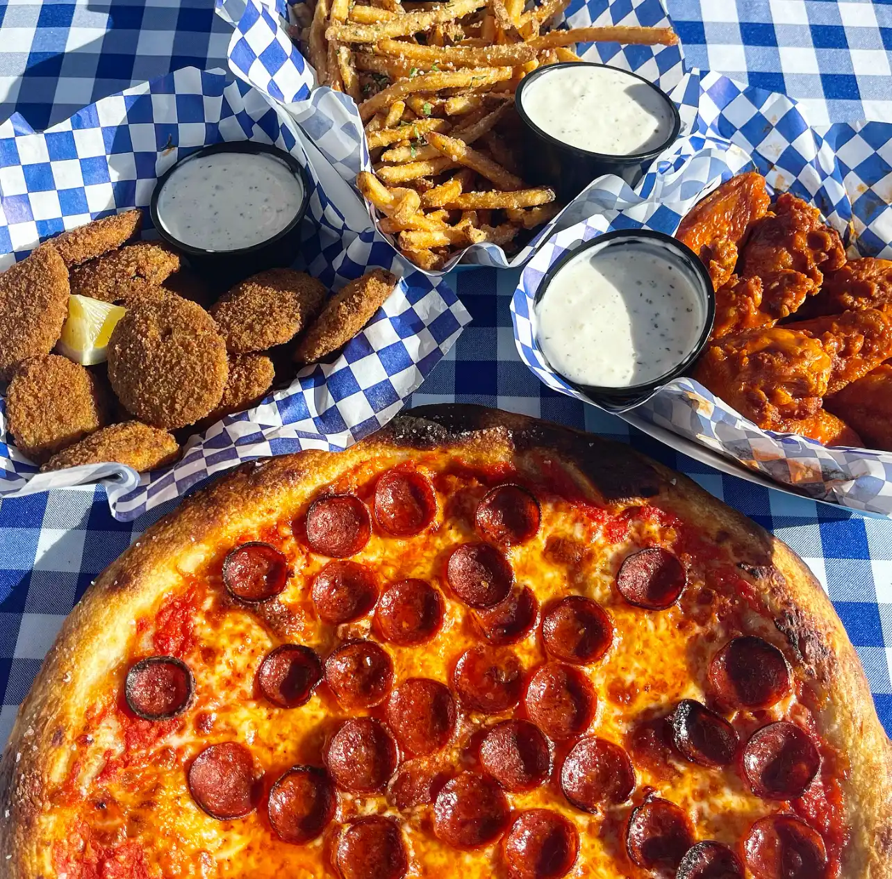 A table of food.  Pizza, Fries, Wings and Fried Zucchini