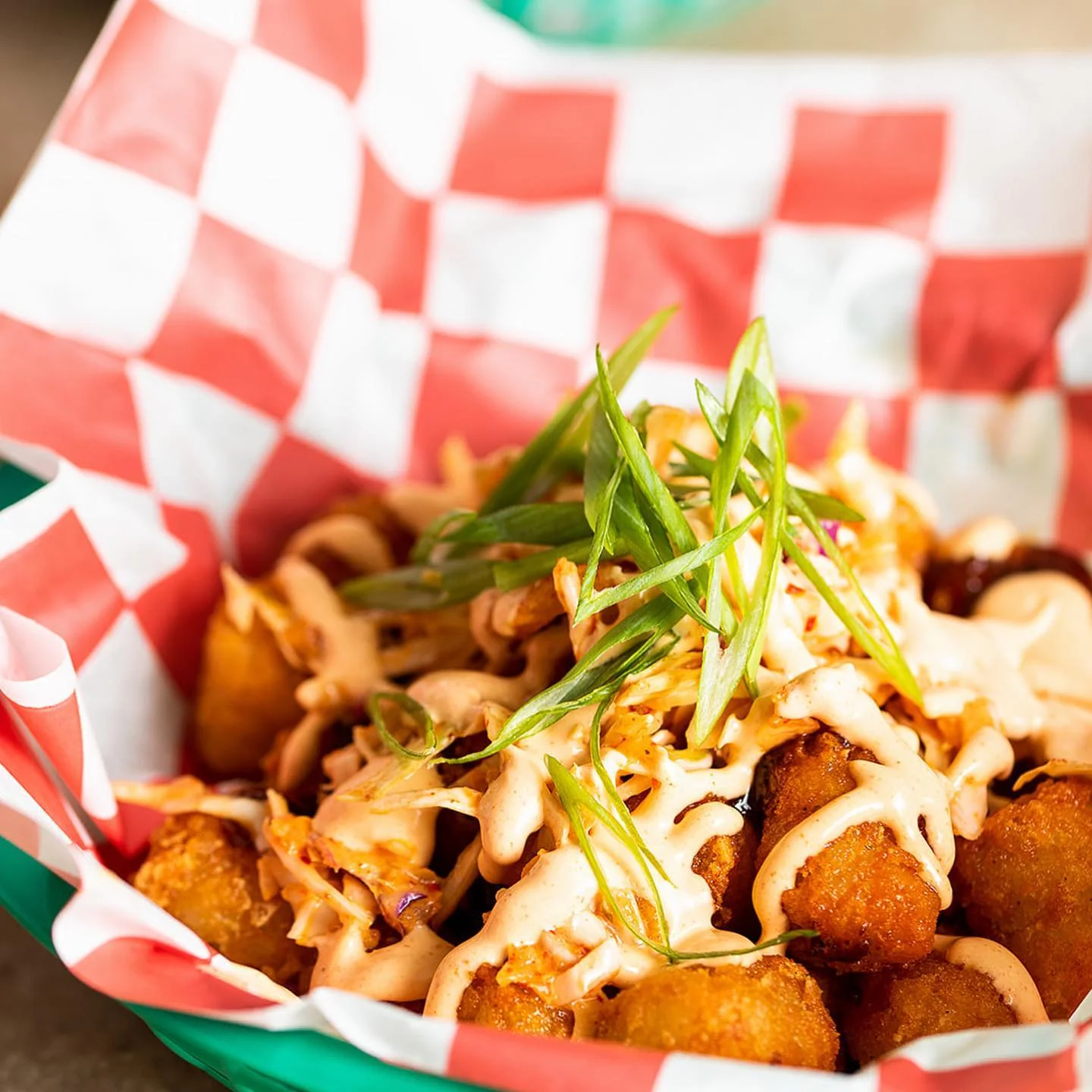 Crispy tater tots topped with spicy sauce and green onions