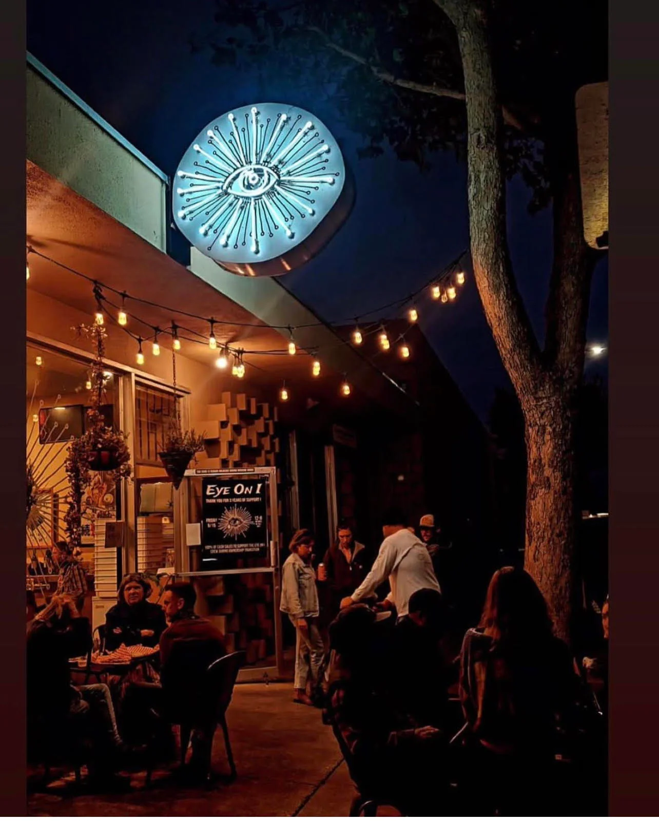 Vibrant restaurant exterior with neon sign and outdoor seating at night