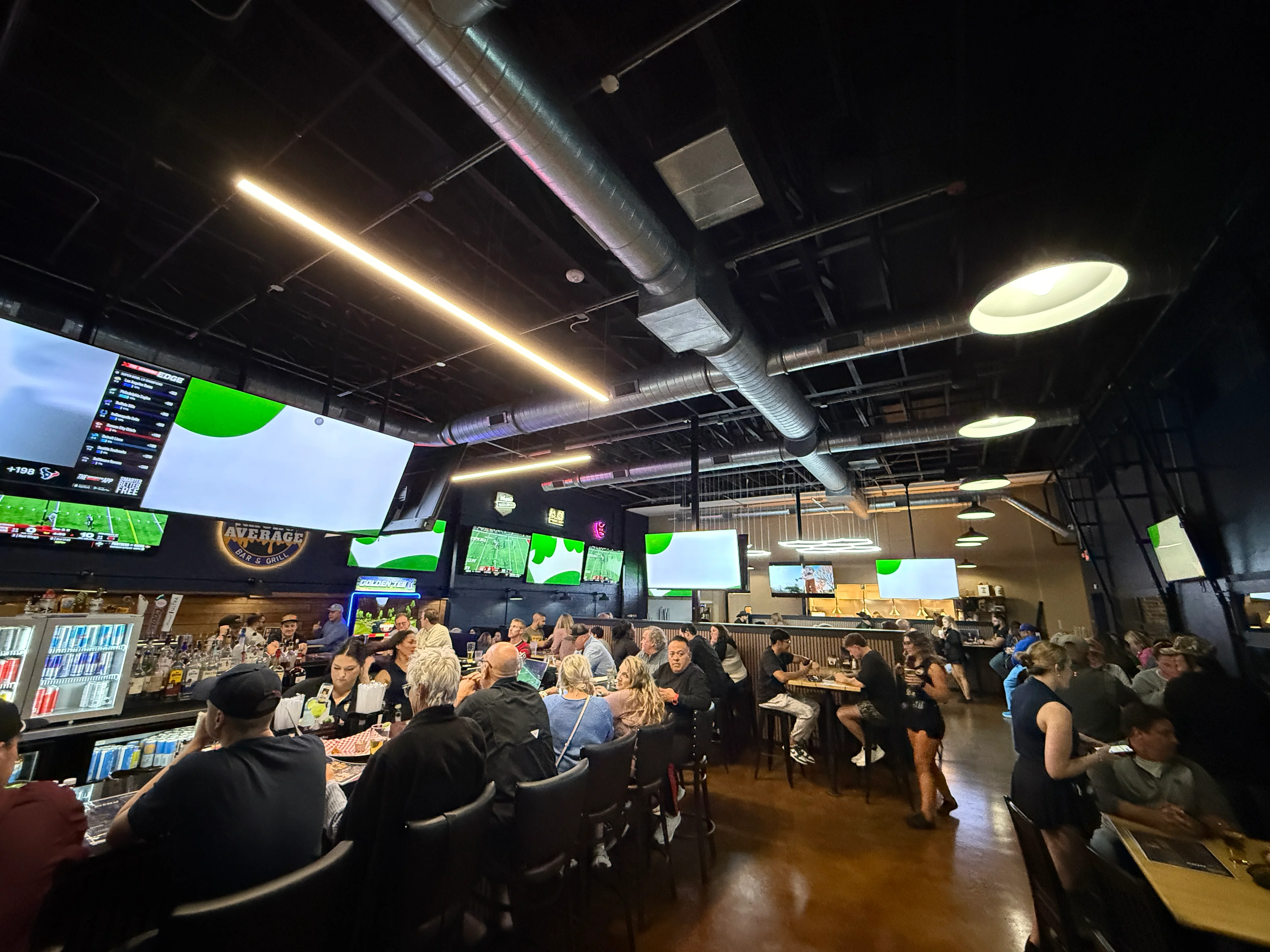 Lively sports bar interior with large screens and patrons enjoying drinks