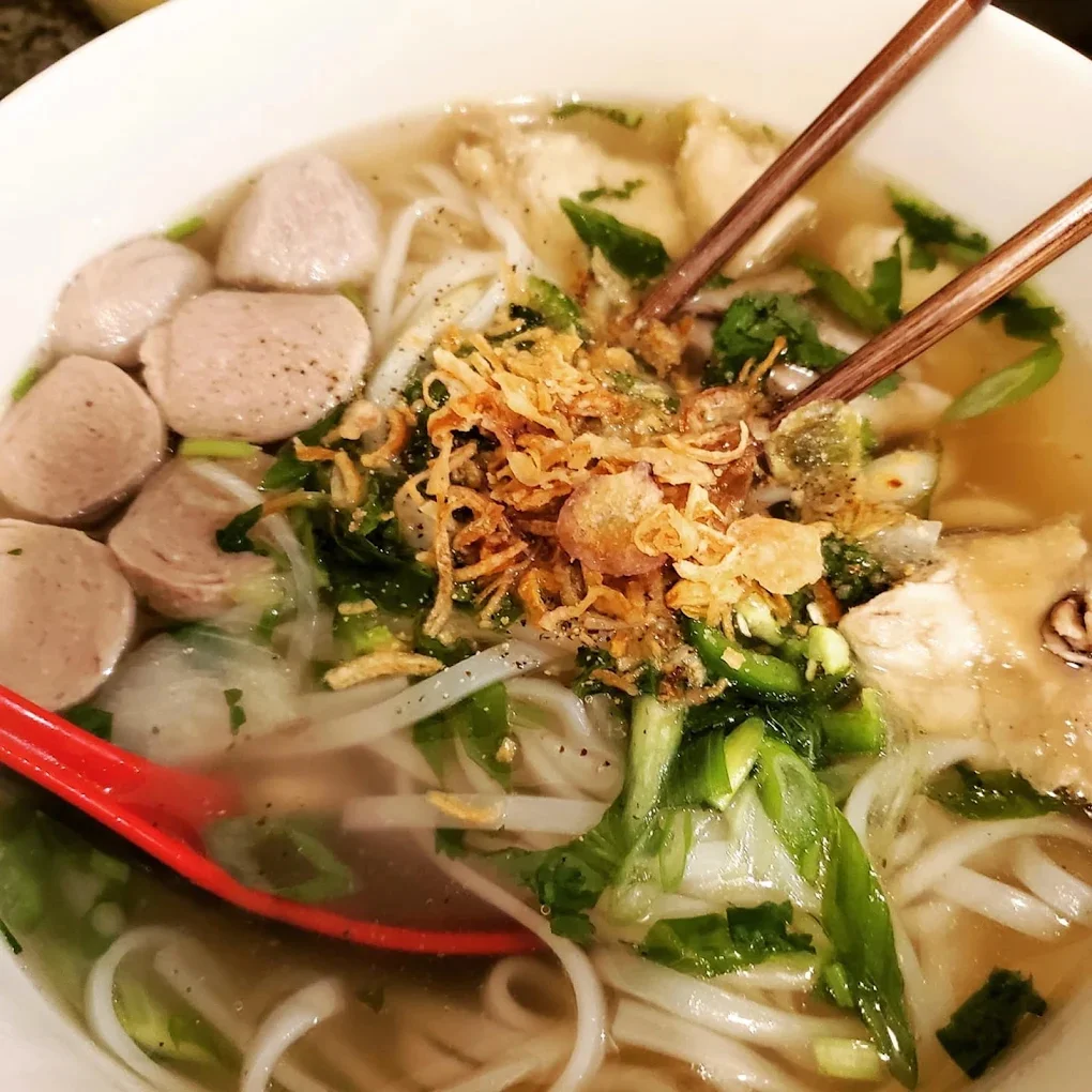 Bowl of Vietnamese pho with meatballs and fresh herbs