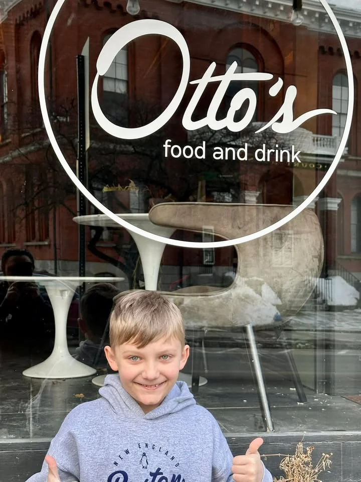 Child smiling in front of Otto's food and drink restaurant