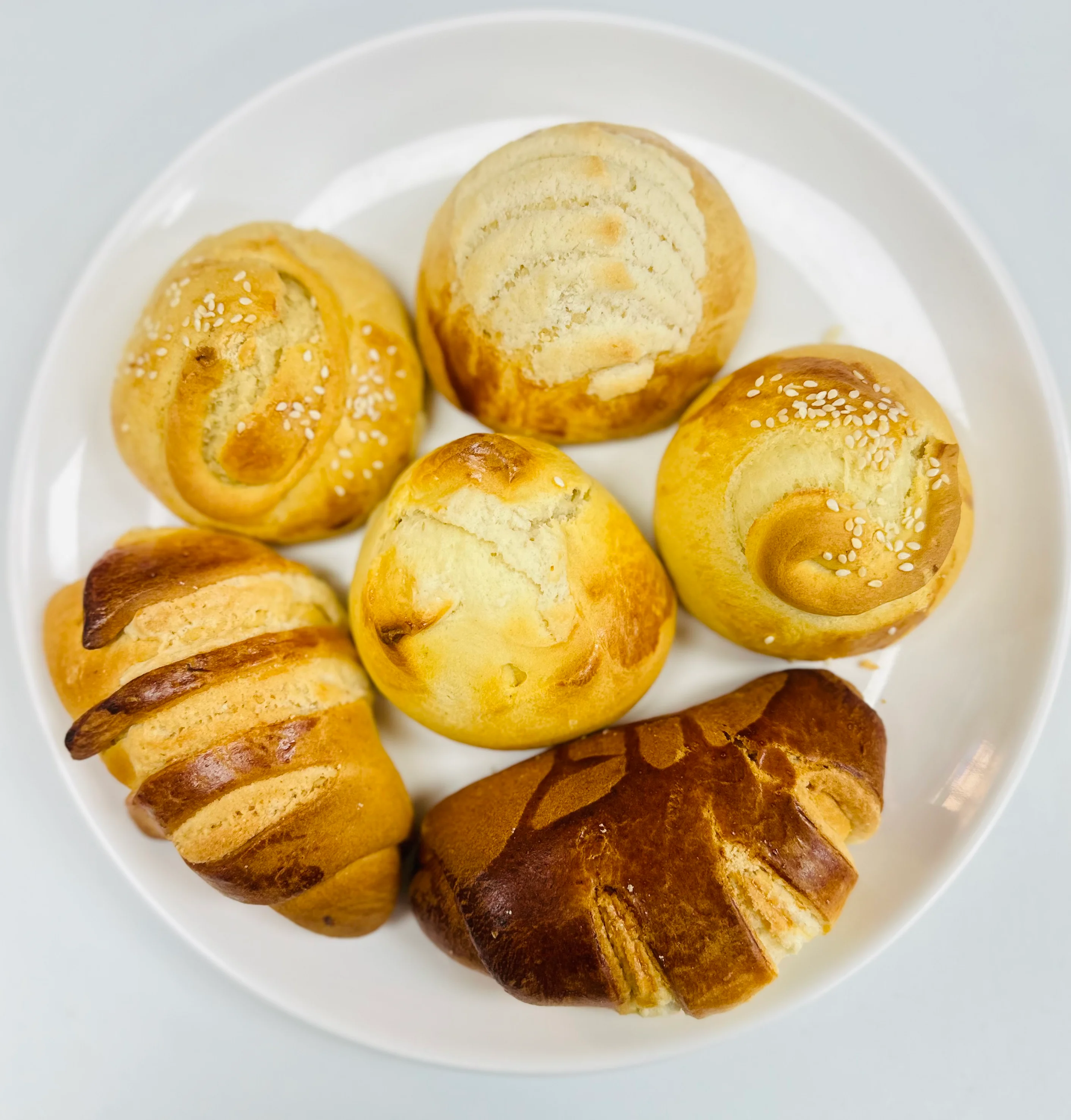 Assorted fresh Brazilian pão de queijo on a white plate