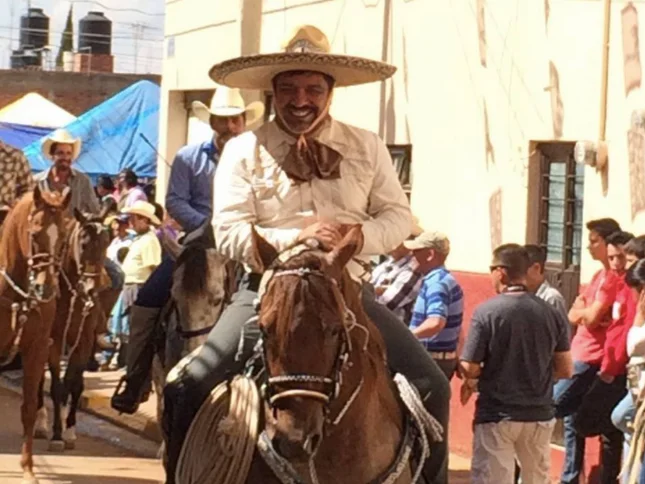 Man in traditional attire riding a horse during a festive parade