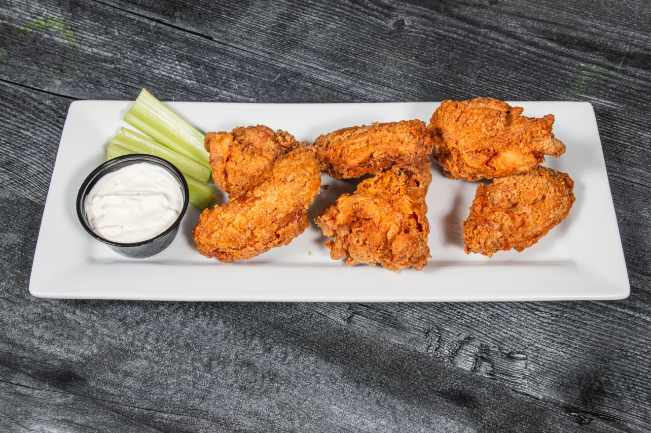 Plate of crispy chicken wings with dipping sauce