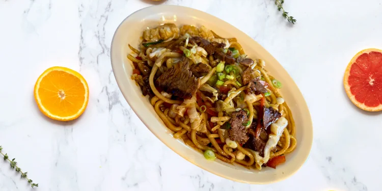 Beef chow mein with vegetables on a white plate