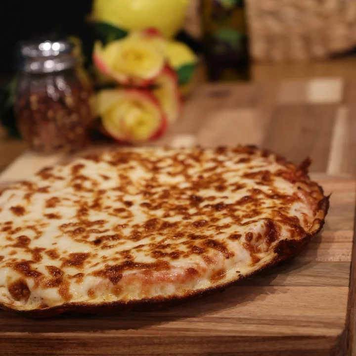A cheese pizza with a perfectly baked crust, presented on a wooden board with decorative elements in the background.