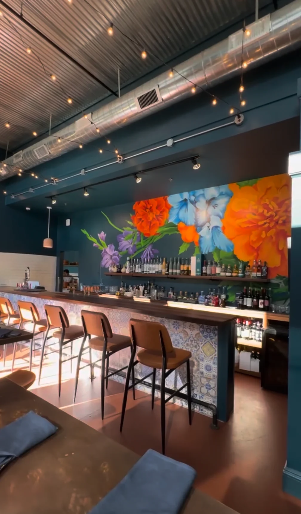 Vibrant restaurant interior with floral mural and bar seating