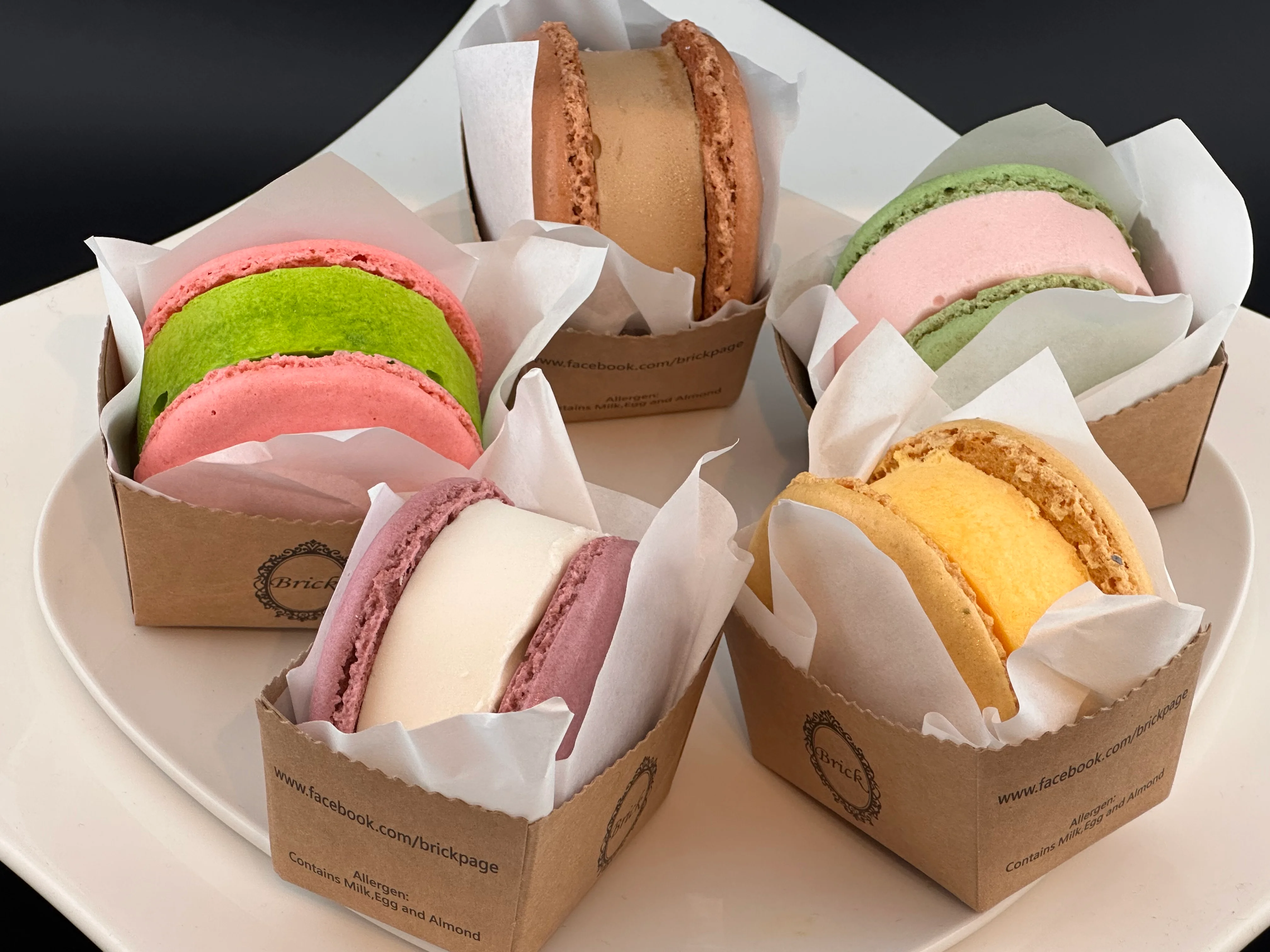 Colorful macarons in paper boxes, showcasing French pastry art