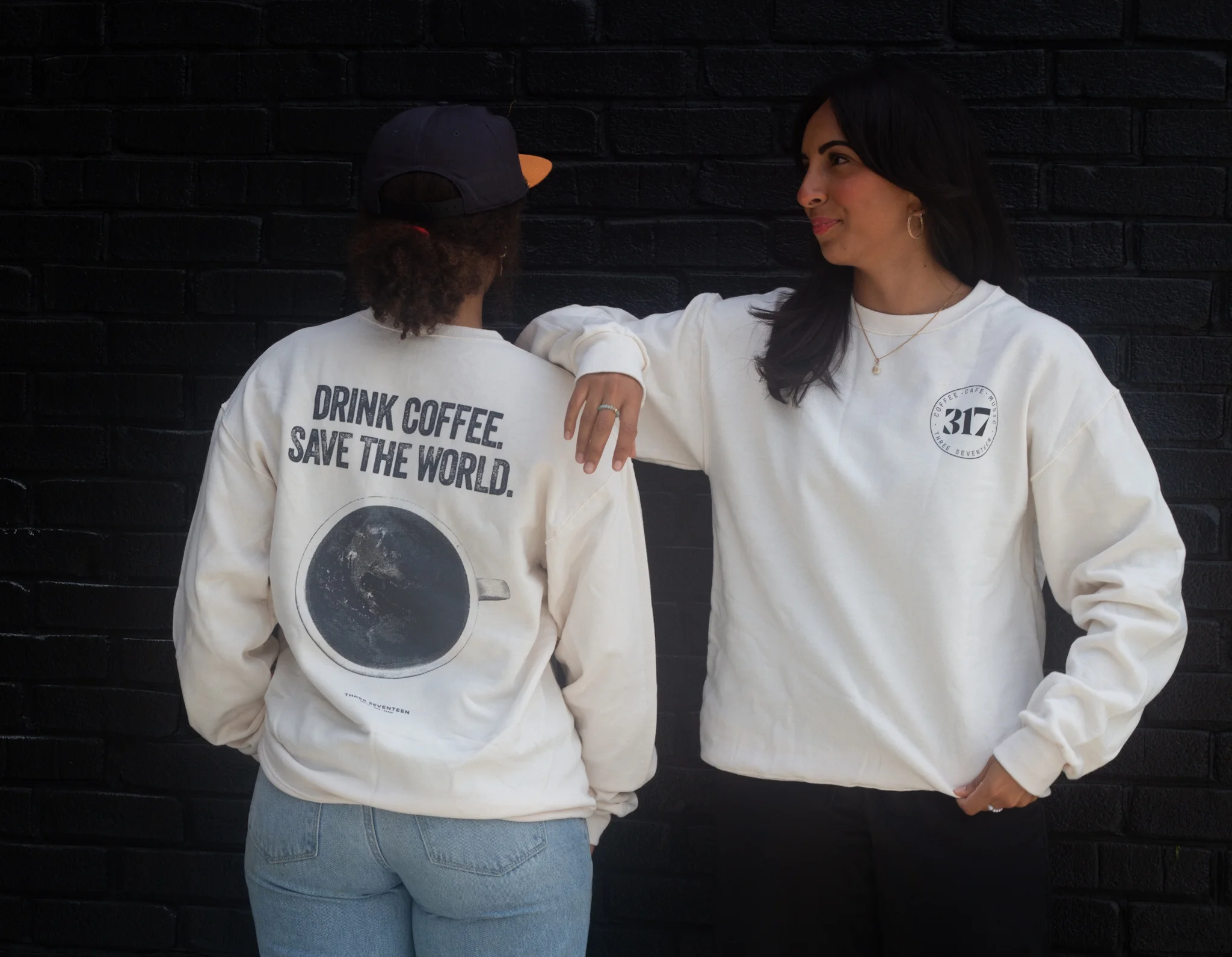 Two women wearing sweatshirts with coffee-themed designs