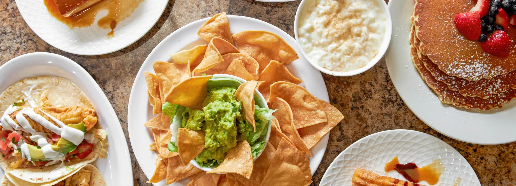 A vibrant spread of popular dishes from El Ranchito Poblano in Brooklyn, highlighting their diverse menu from fresh guacamole to tacos and breakfast pancakes.