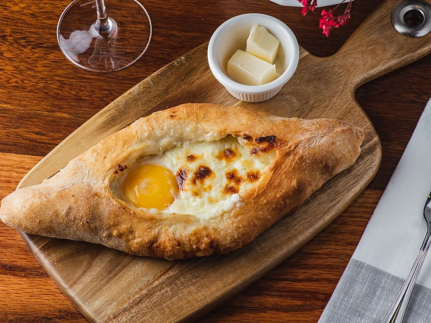 Adjaruli khachapuri with egg and butter on a wooden board