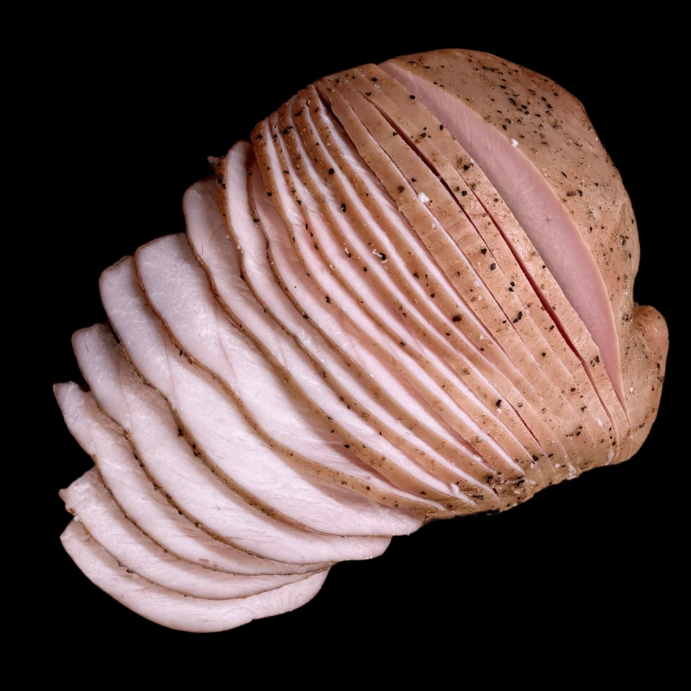 Sliced smoked turkey breast on a black background.